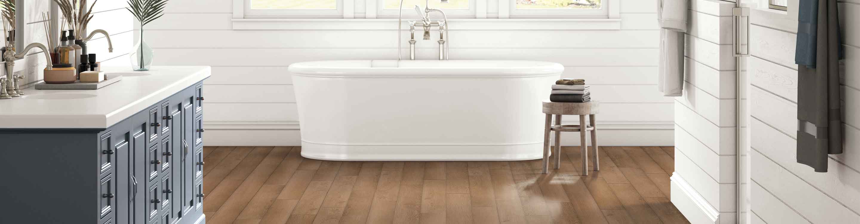 wood vinyl flooring in bathroom with white shiplap walls, blue vanity and deep soak tub